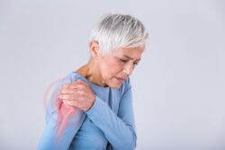 short hair woman with hand over her shoulder pain